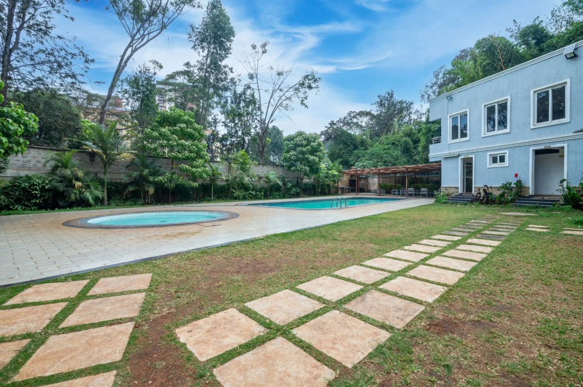 Resort-style swimming pool with manicured lawn and modern villa