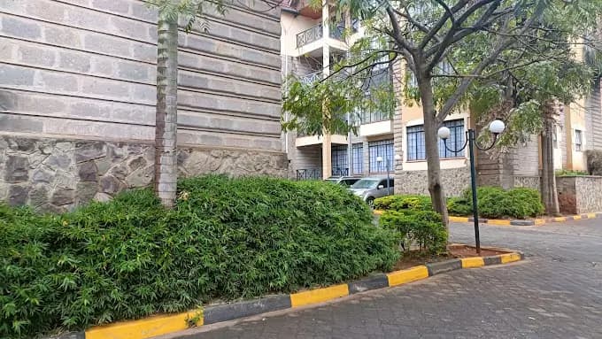 Gated compound entrance with hedges and yellow curb markings
