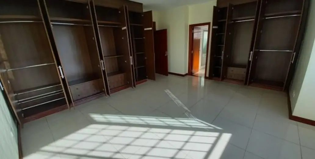 Large empty bedroom with built-in wardrobes and polished floor