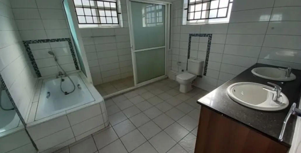 Spacious bathroom with double vanity, shower, and toilet