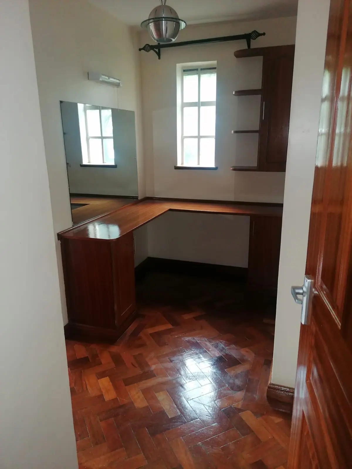 Unfurnished bedroom with wooden desk and herringbone flooring