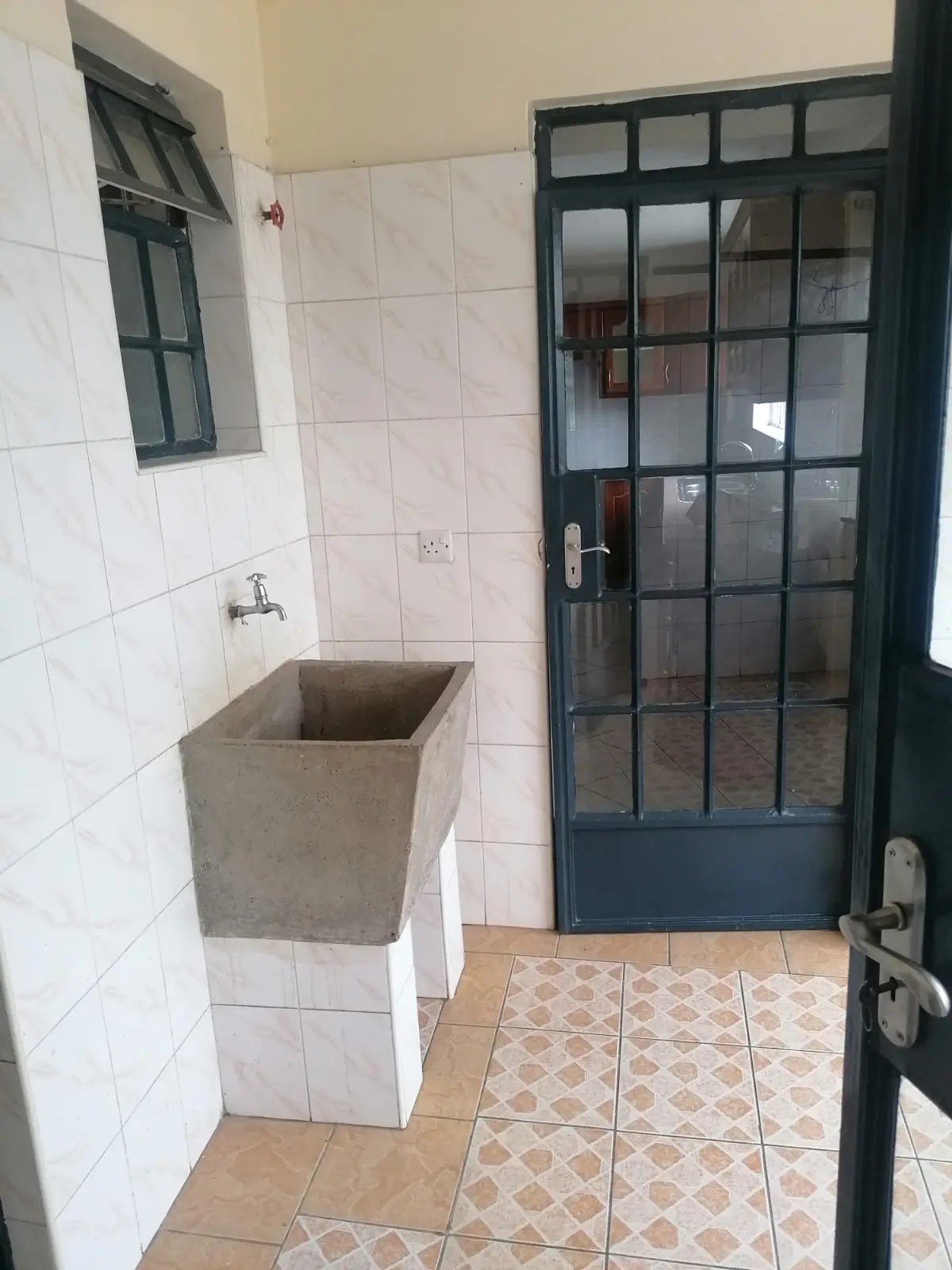 Utility room with concrete sink and tiled flooring