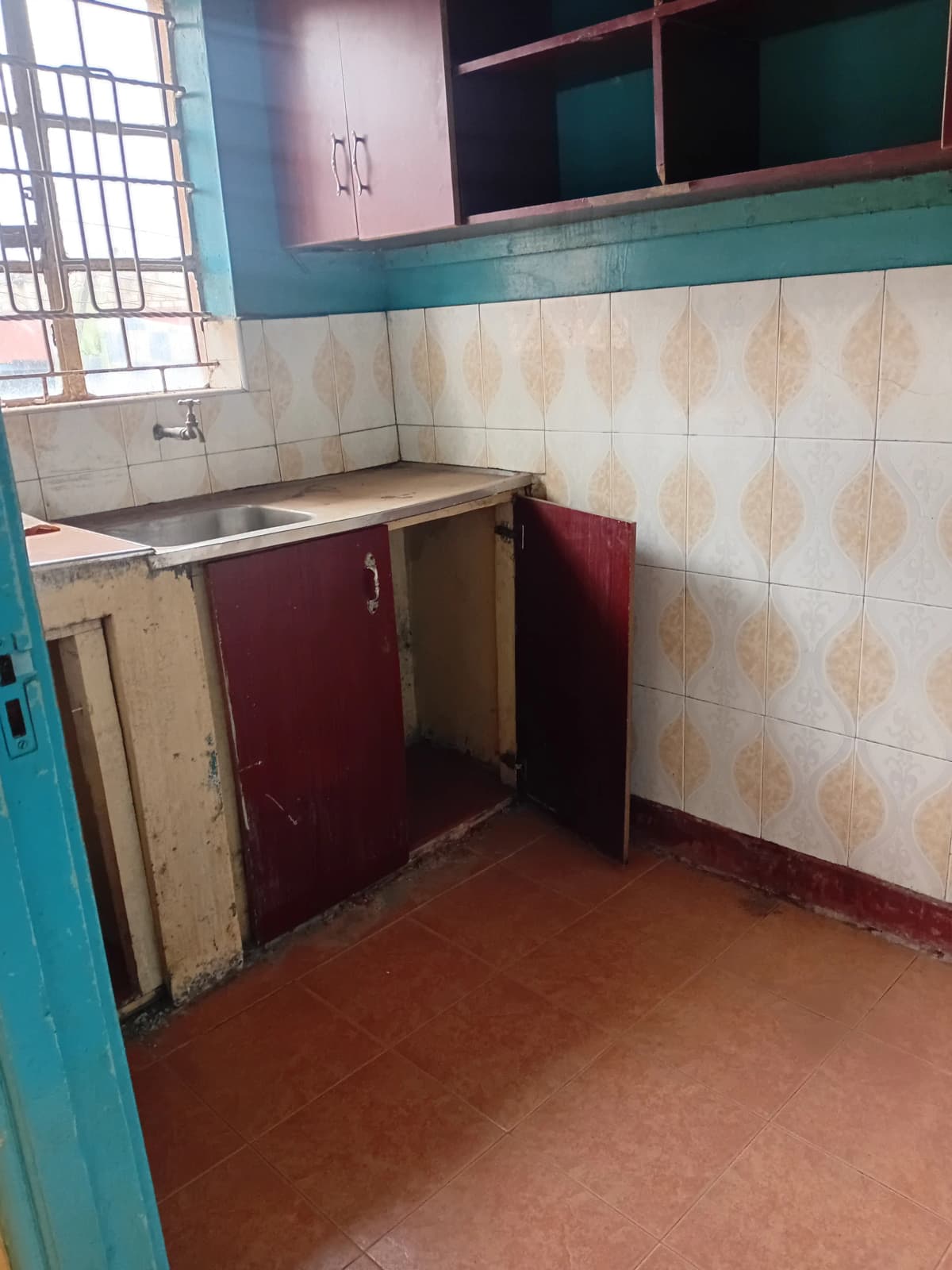 Basic kitchen with stainless sink and worn tile walls