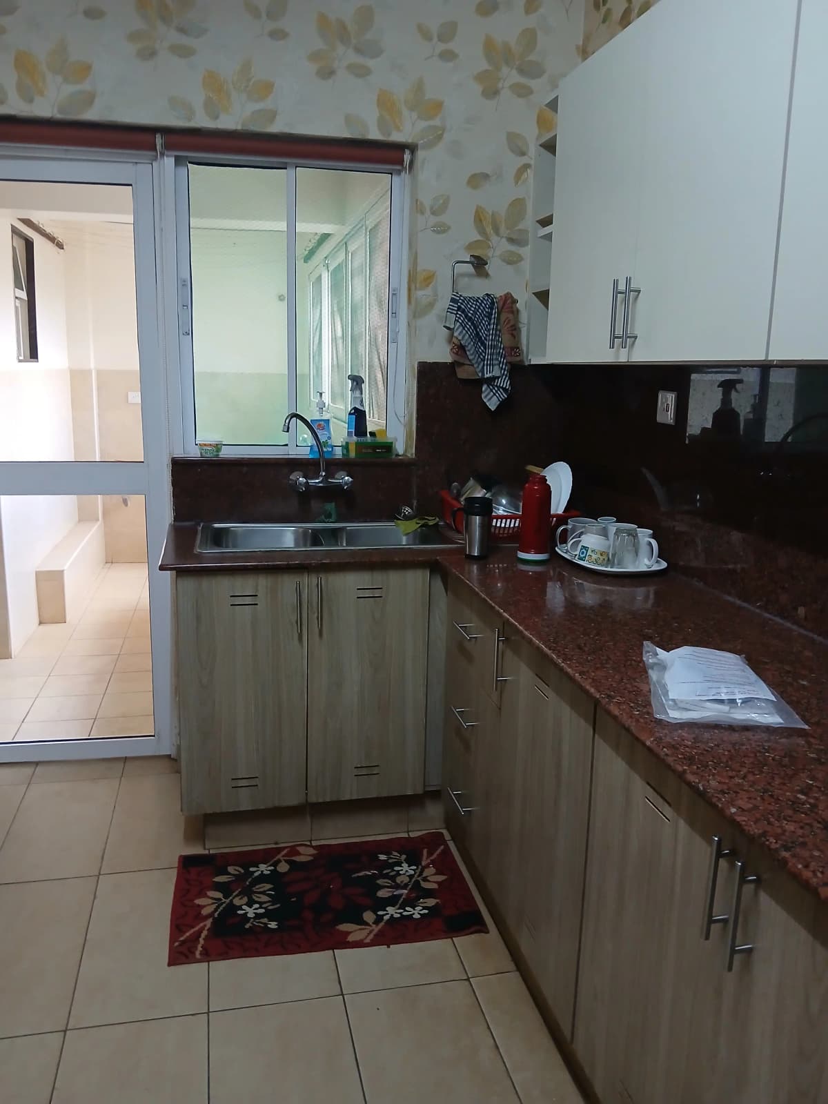 Compact kitchen with sage cabinets, burgundy countertop, mirrored backsplash