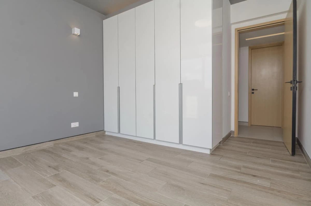 Spacious bedroom with built-in white wardrobes and wooden flooring