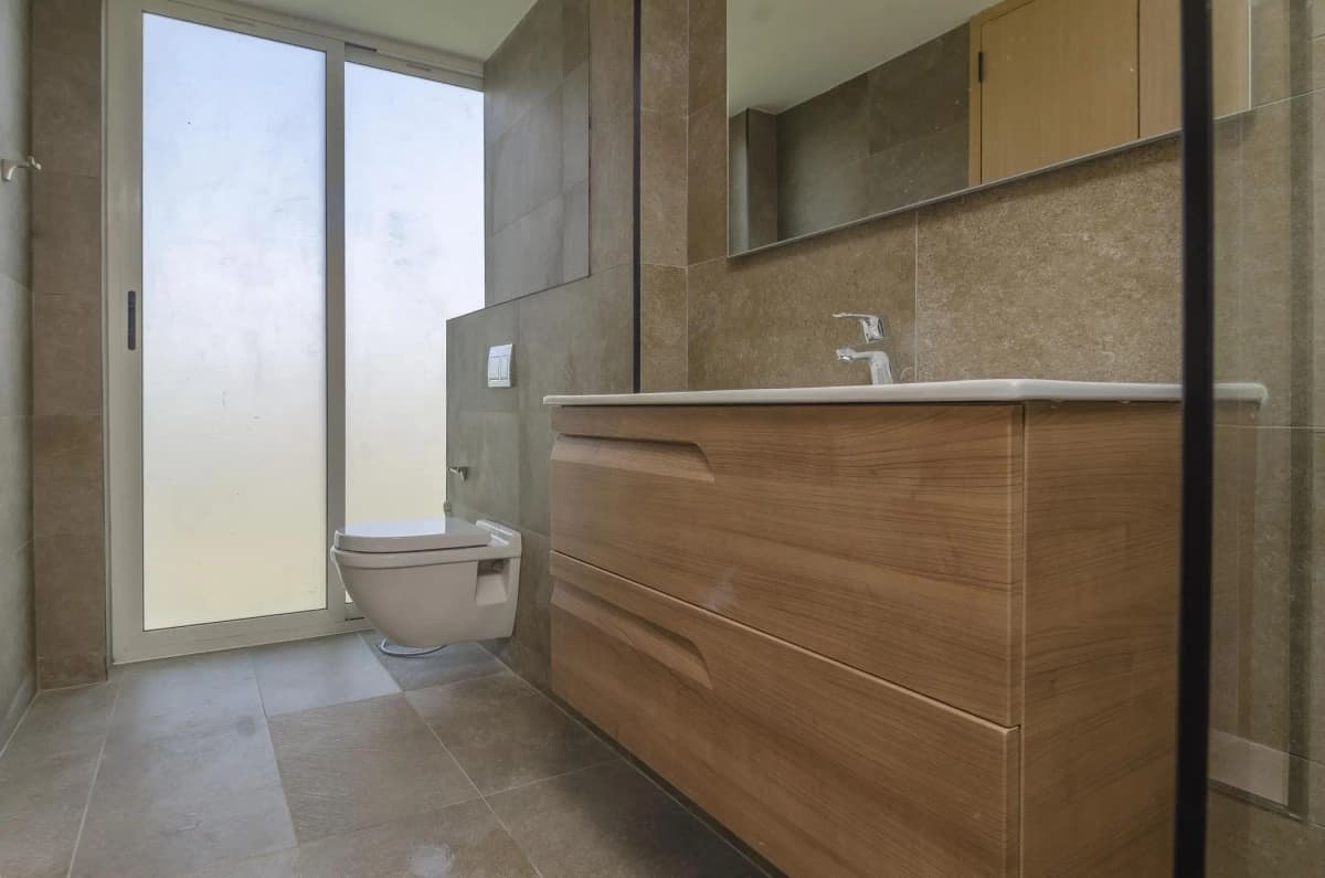 Modern bathroom with wooden vanity and frosted glass shower enclosure