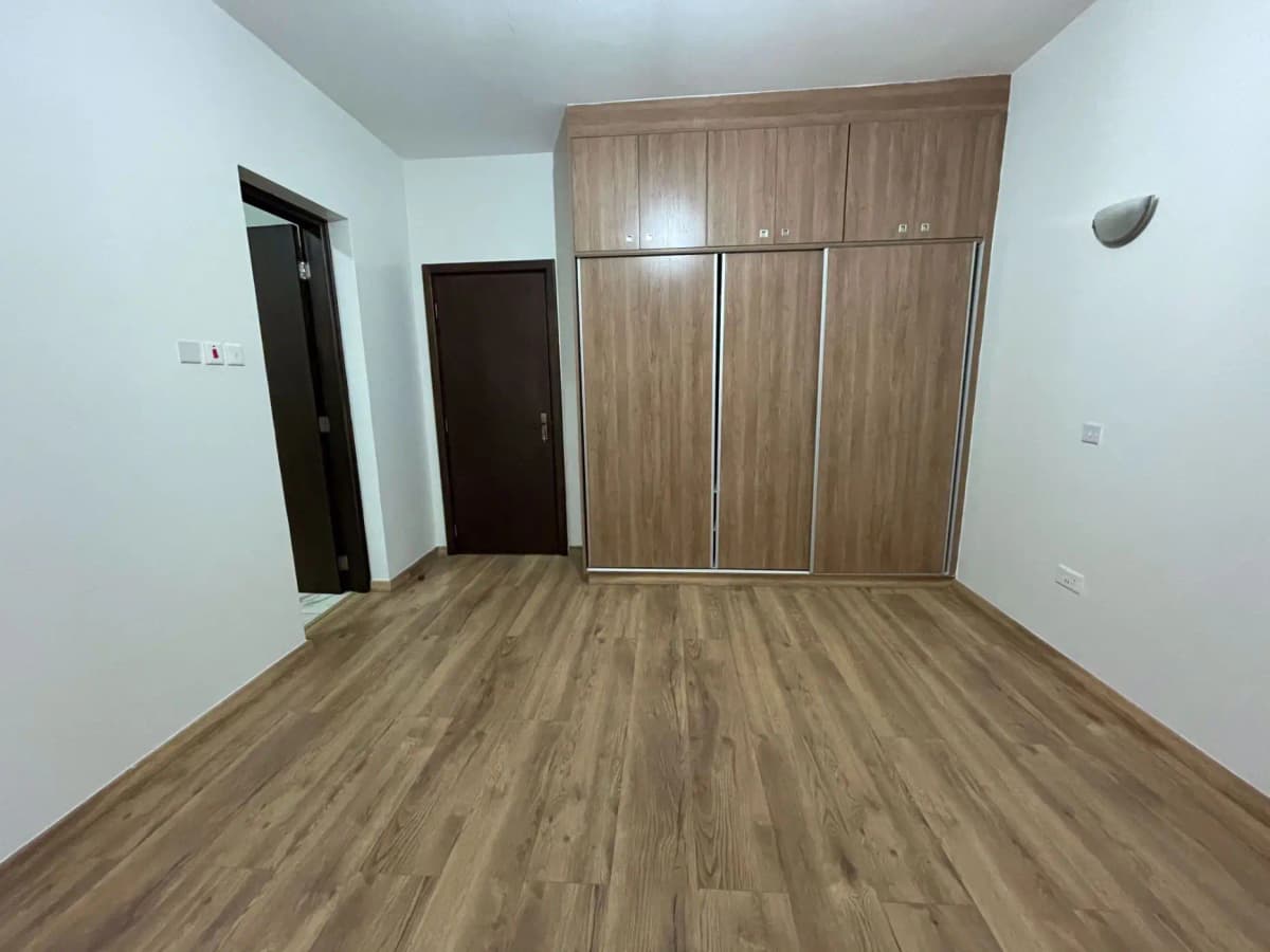Spacious bedroom with wooden wardrobe and laminate flooring