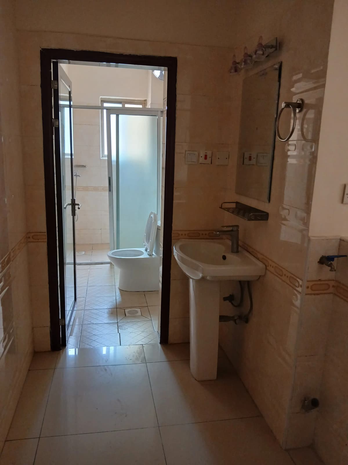 Compact bathroom with pedestal sink and enclosed shower