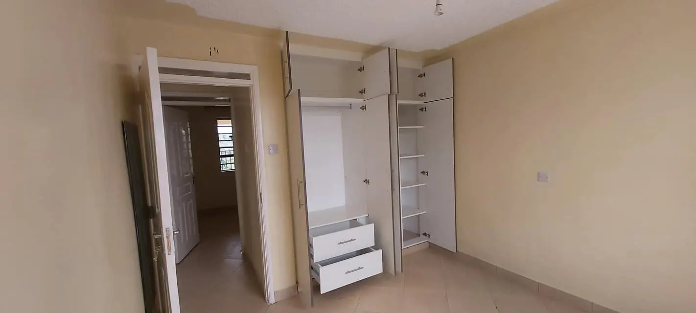 Unfurnished bedroom with built-in wardrobes and open door
