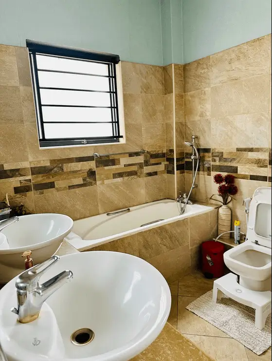 Bathroom with dual sinks, bathtub, and decorative tile work