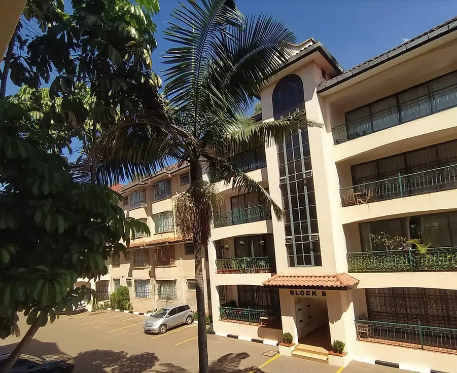 Multi-story residential building with palm trees and parking area
