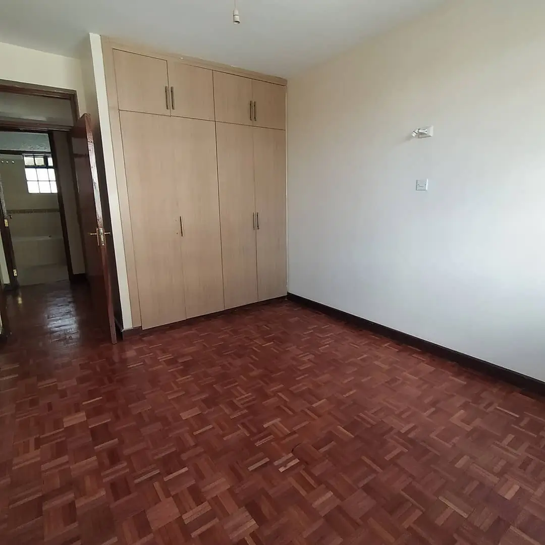 Spacious bedroom with built-in wooden wardrobe and parquet flooring