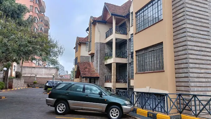 Multi-story residential building with parking bay and compound entrance