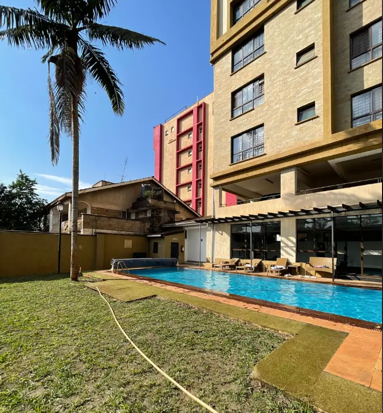 Residential pool with manicured lawn and modern apartment building