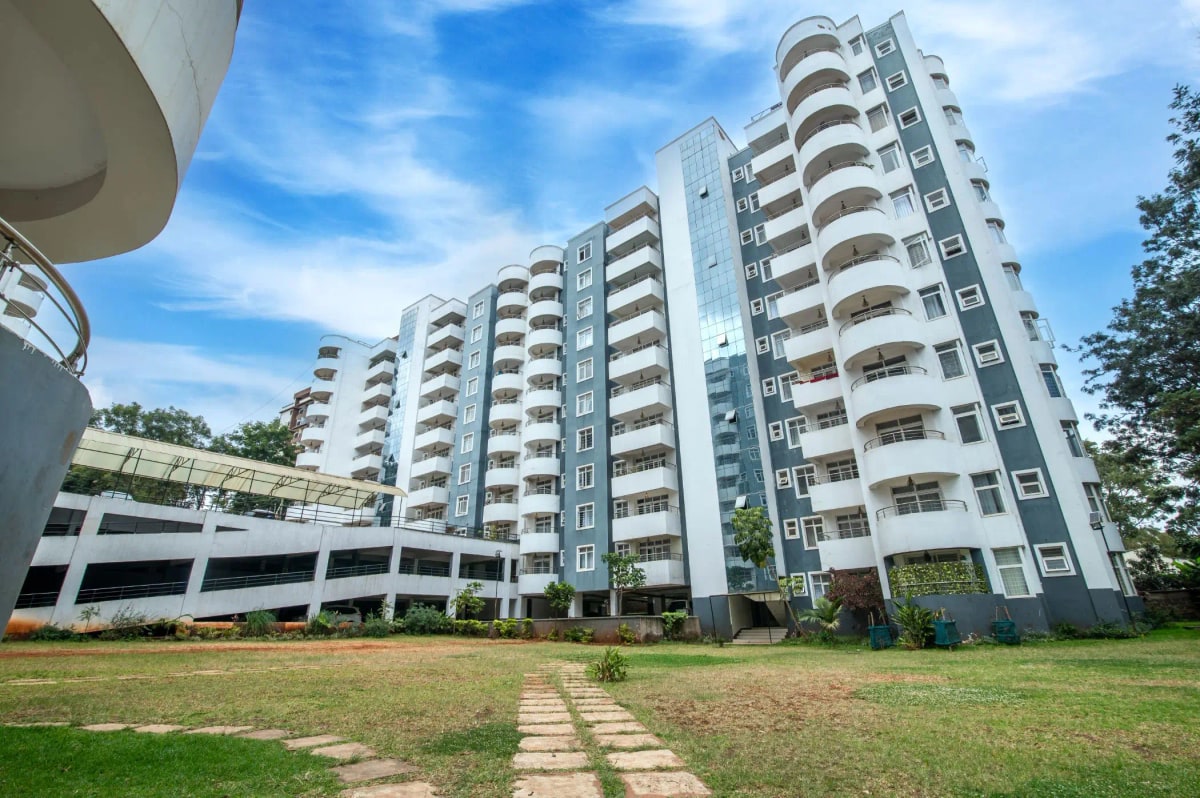 Modern multi-story residential building with manicured compound grounds