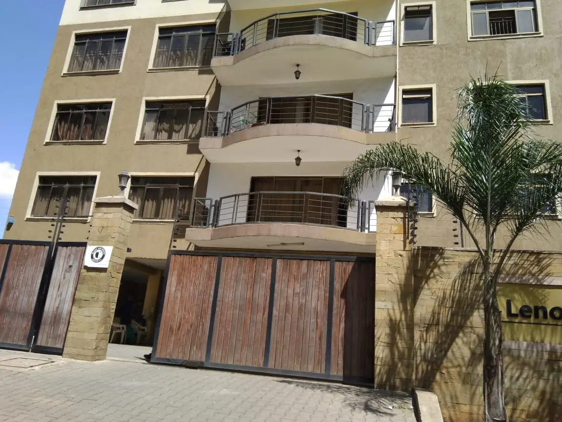 Modern multi-story apartment building with curved balconies and wooden gates