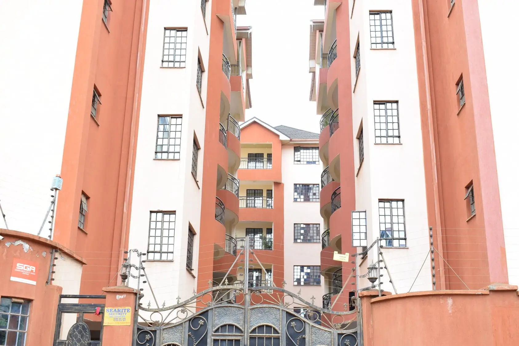 Multi-story residential building facade with coral-pink coloring