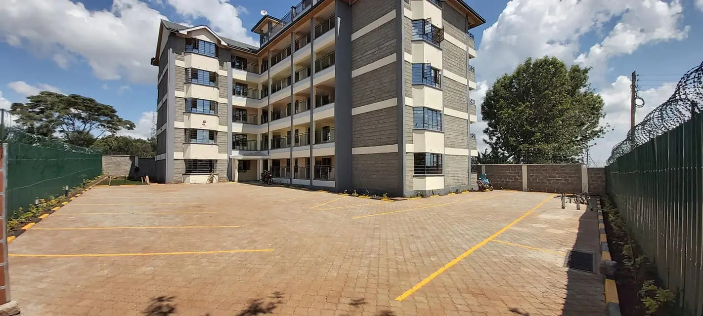 Large paved parking lot with residential building backdrop