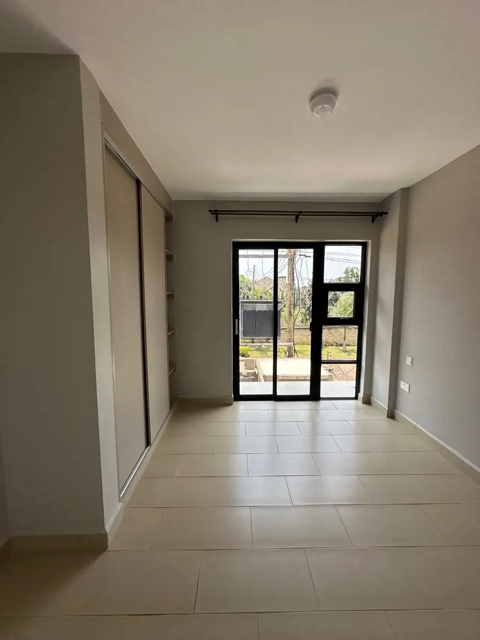 Bright corridor with tiled flooring and glass doors to garden