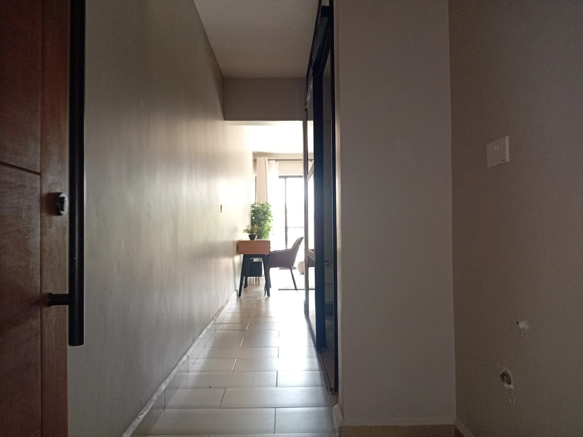 Bright hallway with tile flooring, potted plant, open door