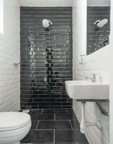 Modern bathroom with black tile shower, white sink, toilet
