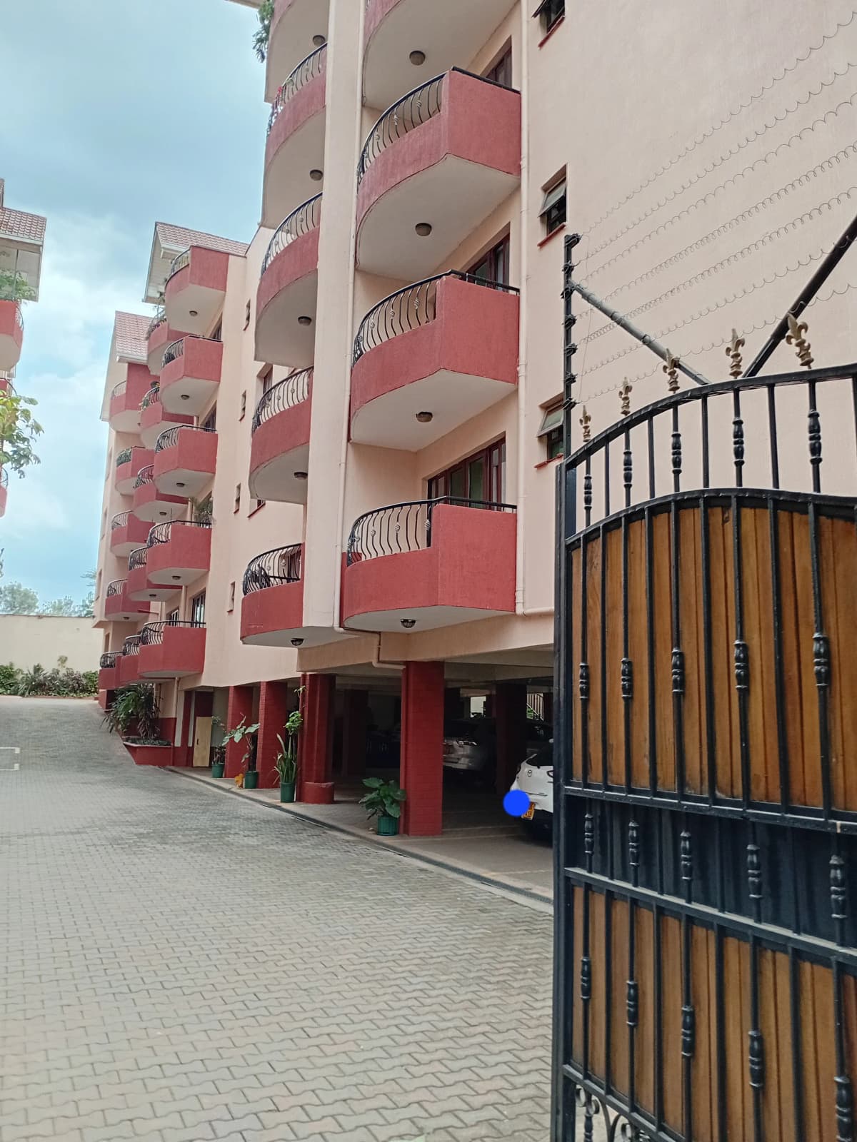 Multi-story residential building with red balconies and entrance gate