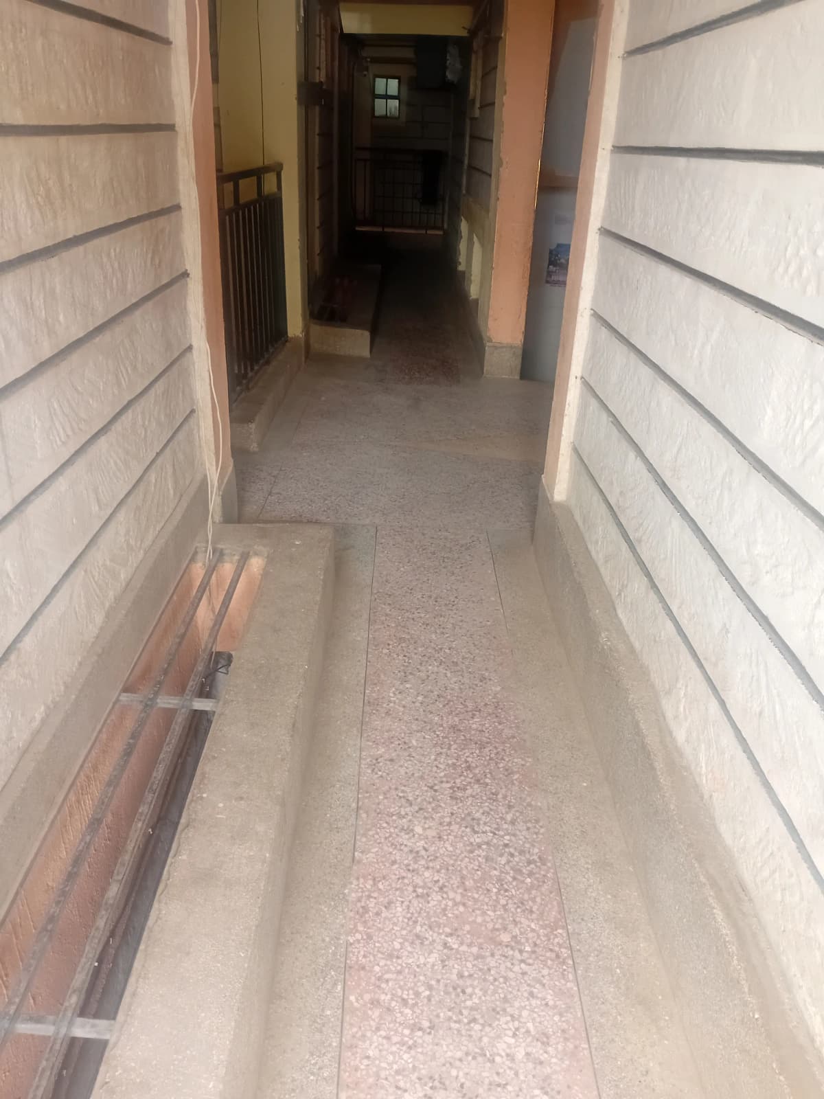 Narrow corridor with tiled flooring leading to entrance