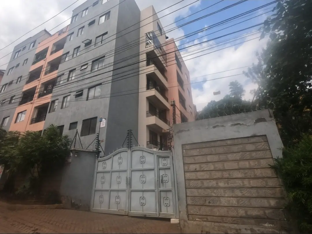 Multi-story residential building with metal gate and driveway entrance