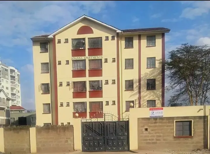 Yellow residential apartment building with red balconies and gate