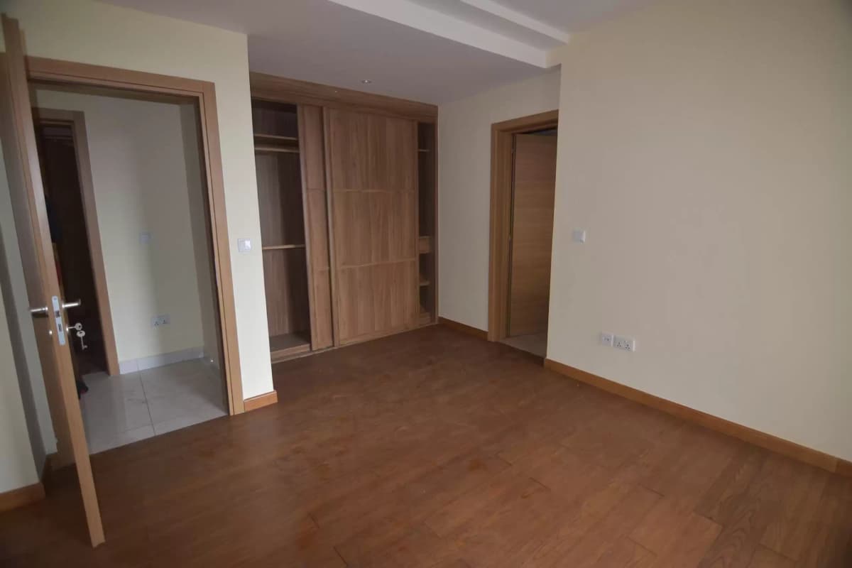Spacious empty living room with wooden floor and multiple doors