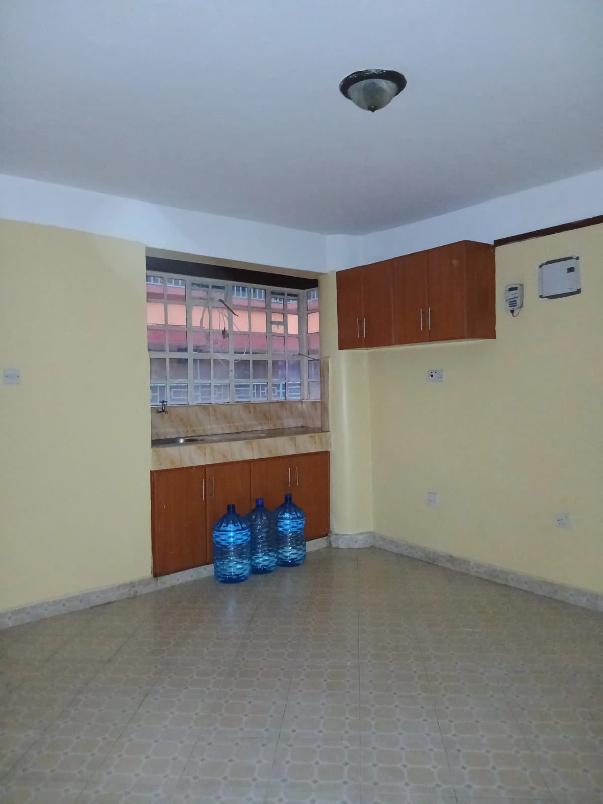 Compact kitchen with brown cabinetry and window overlooking street