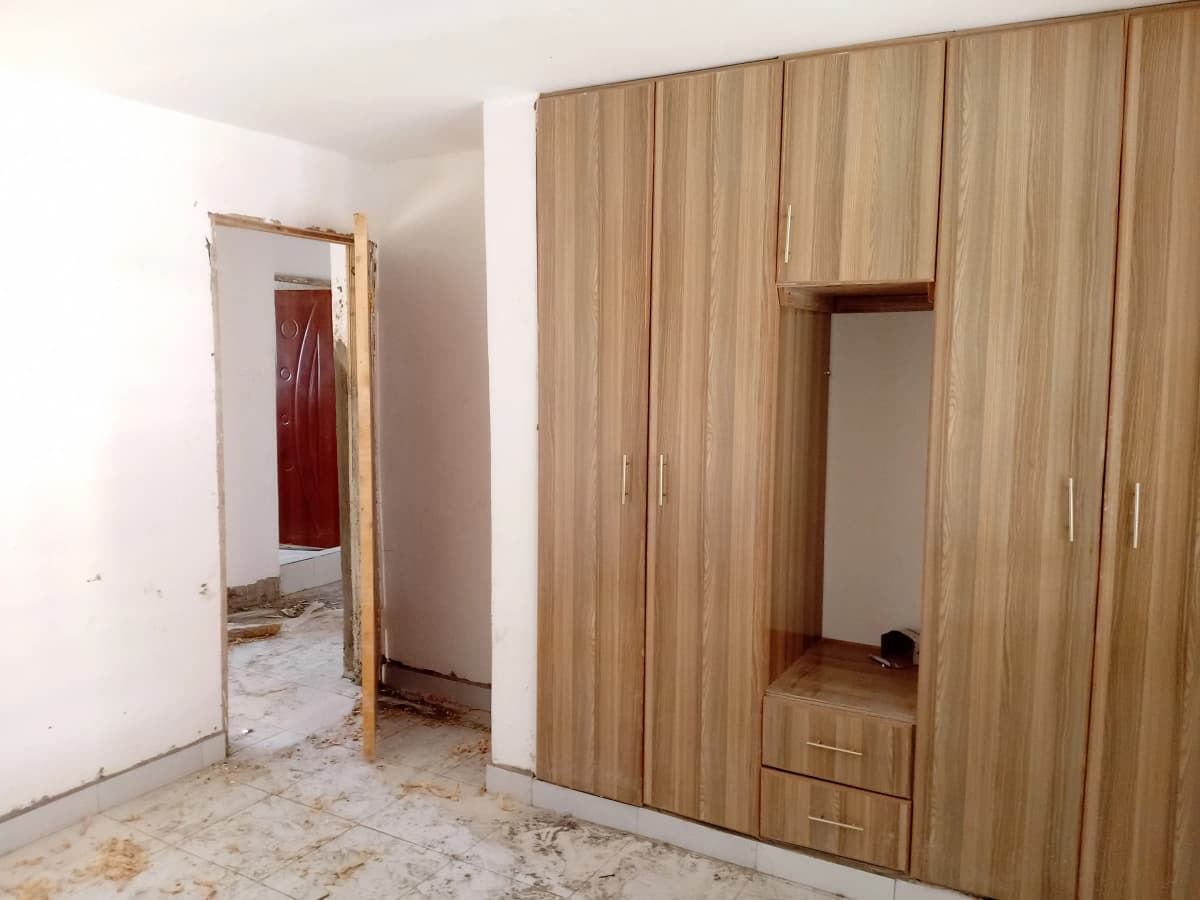 Unfurnished bedroom with wooden wardrobe and tiled floor