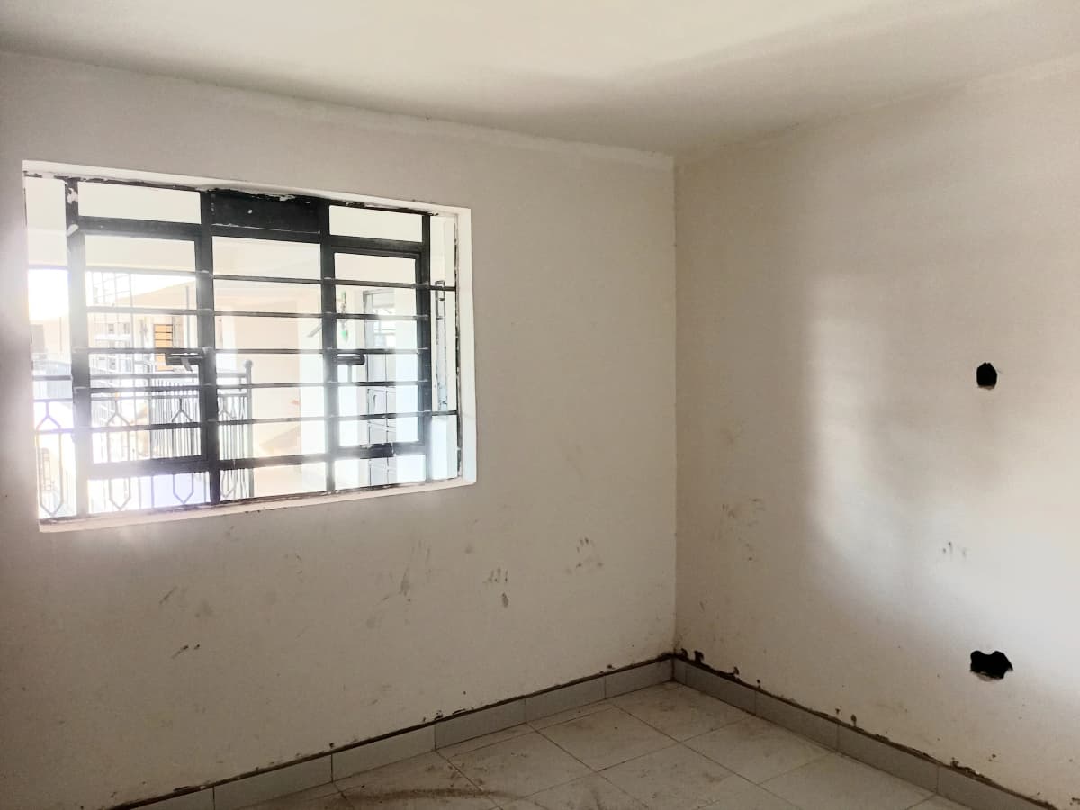 Unfurnished bedroom with barred window and concrete floor