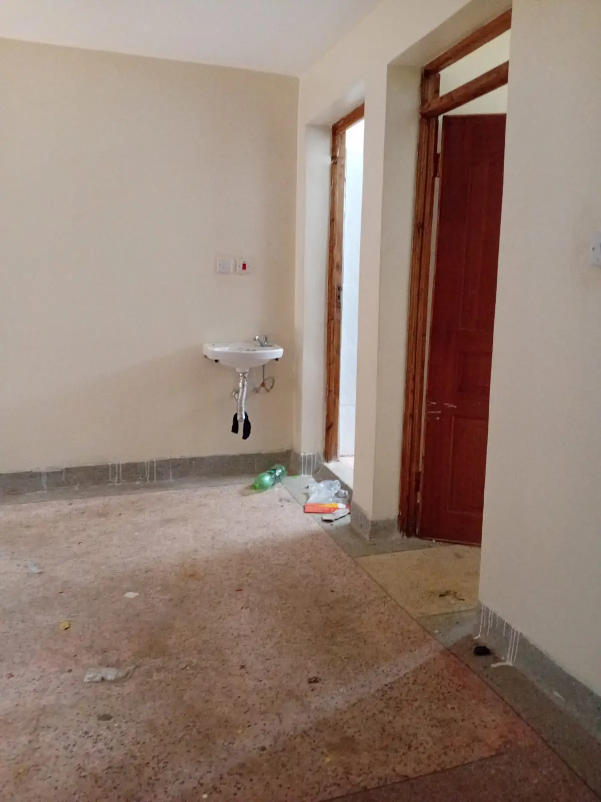 Bathroom with wall-mounted sink, red door, under construction
