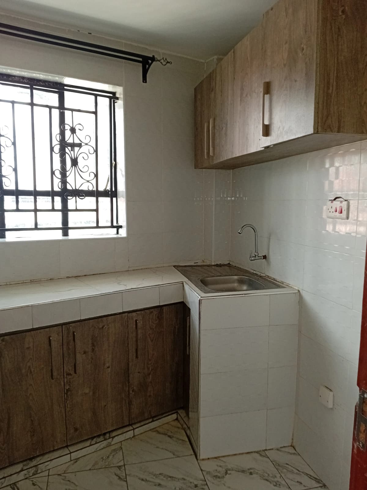 Compact kitchen with wooden cabinetry, sink, and washing machine