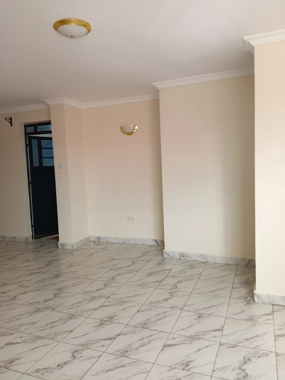 Empty living space with marble tile flooring and white walls