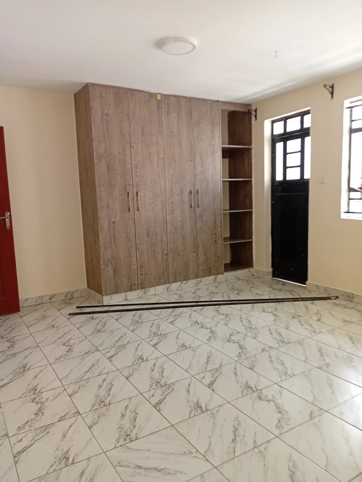 Spacious bedroom with built-in wooden wardrobe and marble flooring
