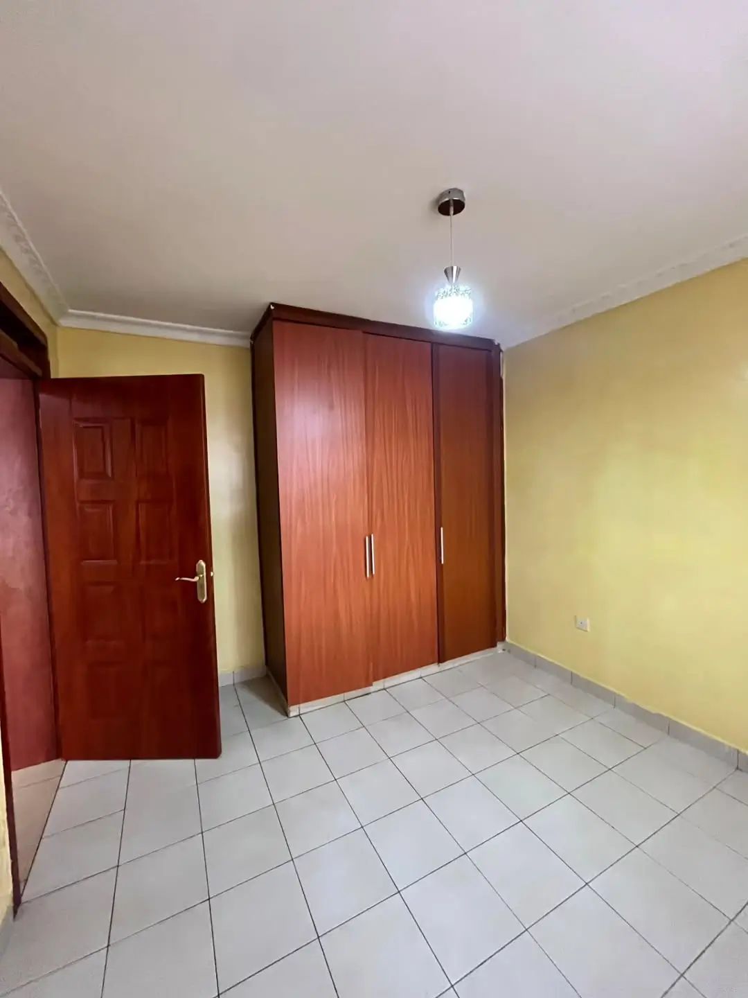 Spacious bedroom with wooden wardrobes and yellow walls