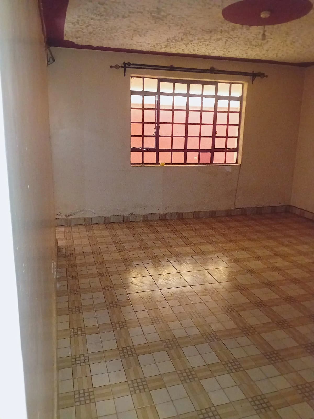 Empty bedroom with terracotta tile floor and barred window