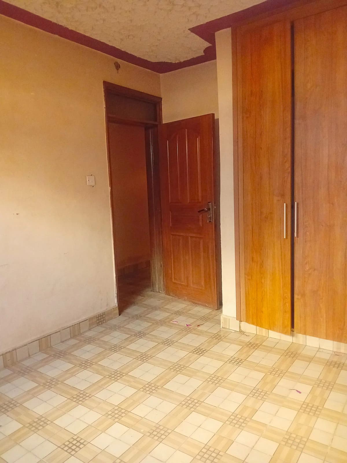 Empty bedroom with tiled floor and wooden wardrobes