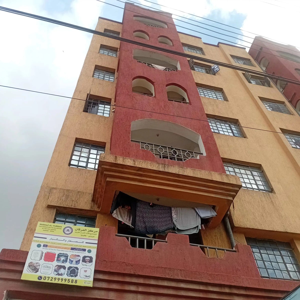 Multi-story residential building facade with red and beige panels