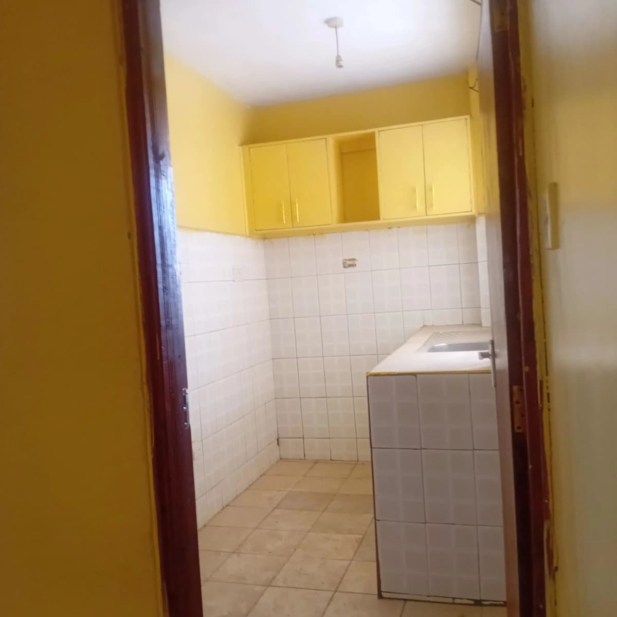 Compact kitchen with yellow cabinets and white tiled walls