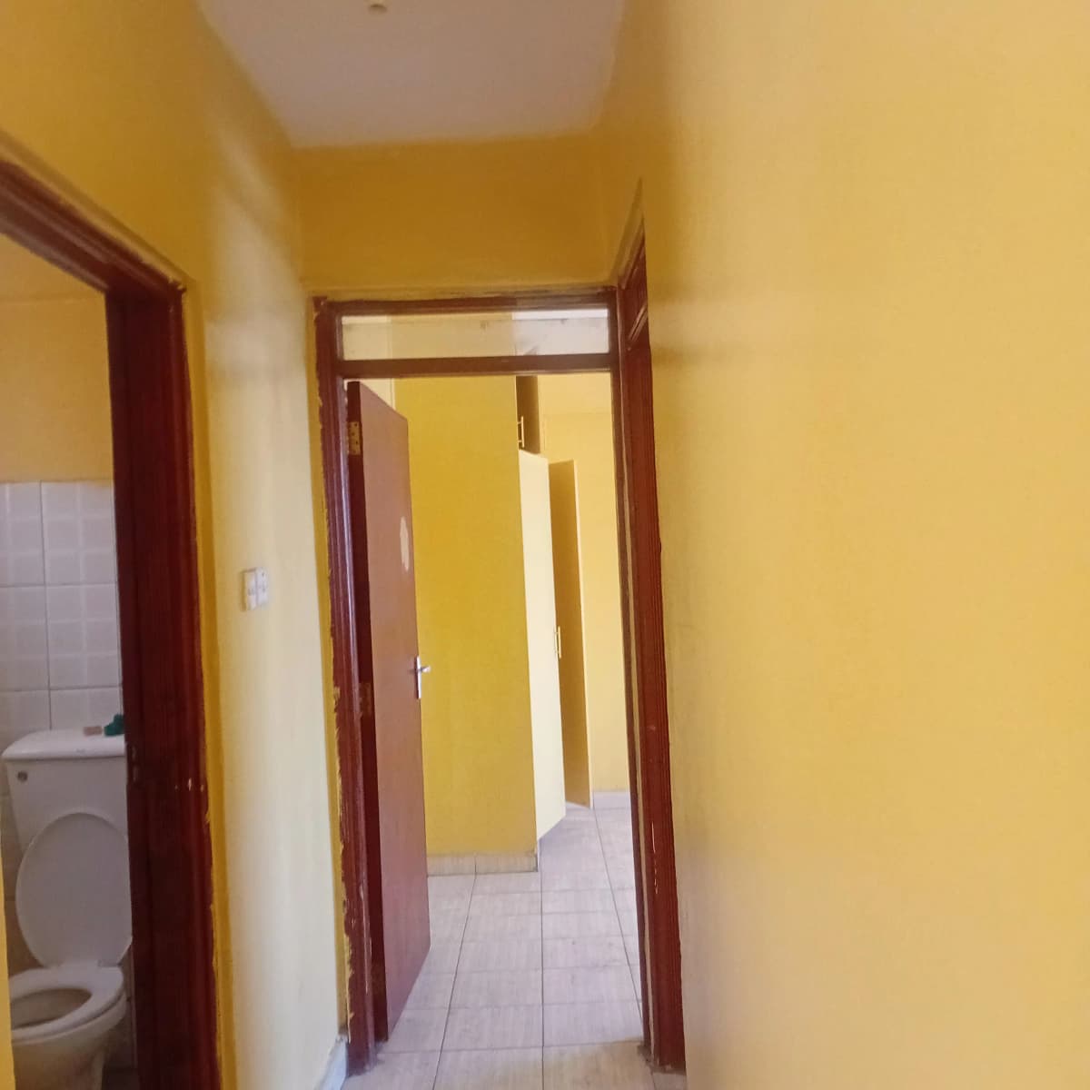 Bright yellow hallway with wooden door frames and tile flooring
