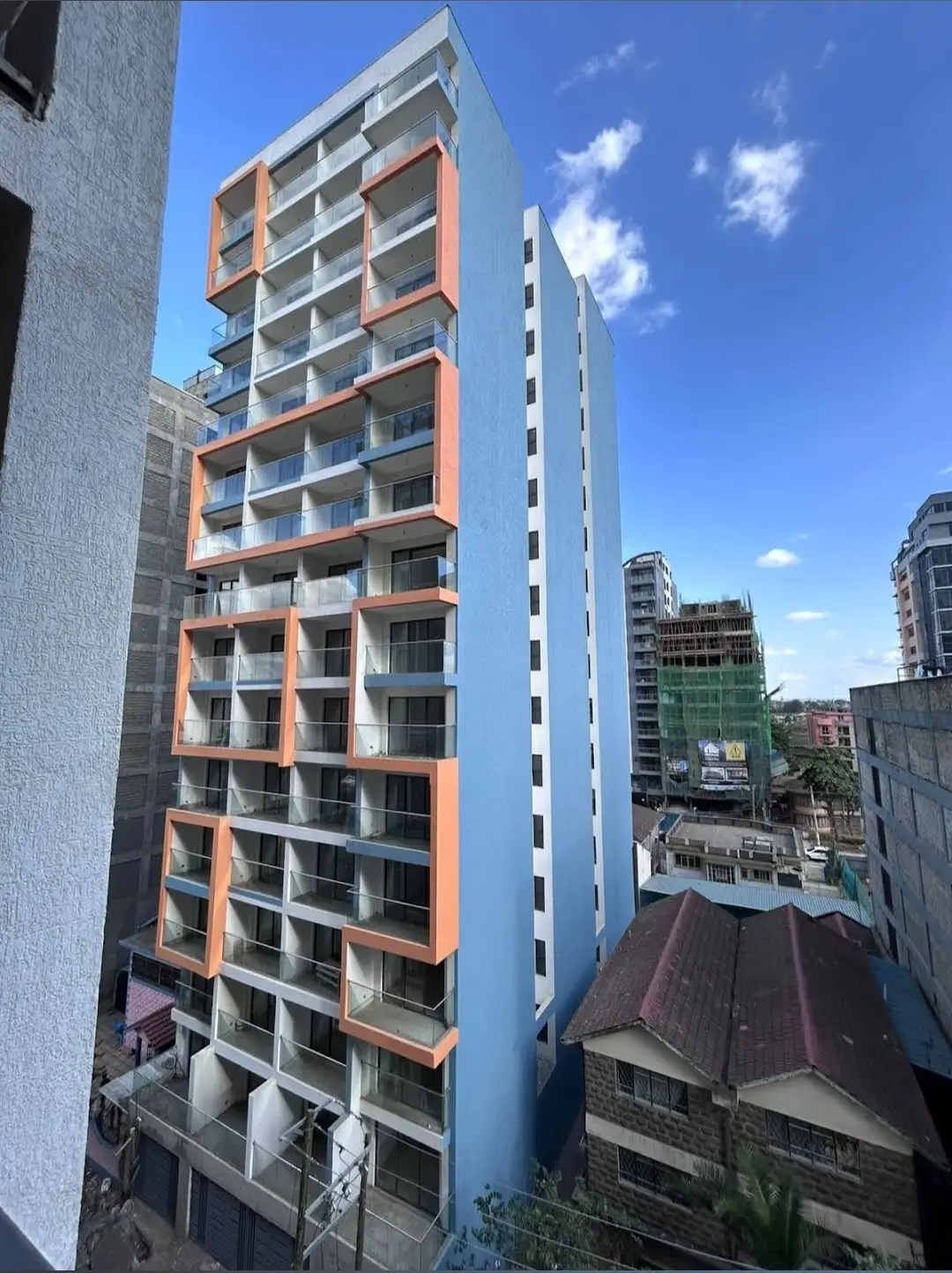 Modern multi-story residential building with orange and gray facade
