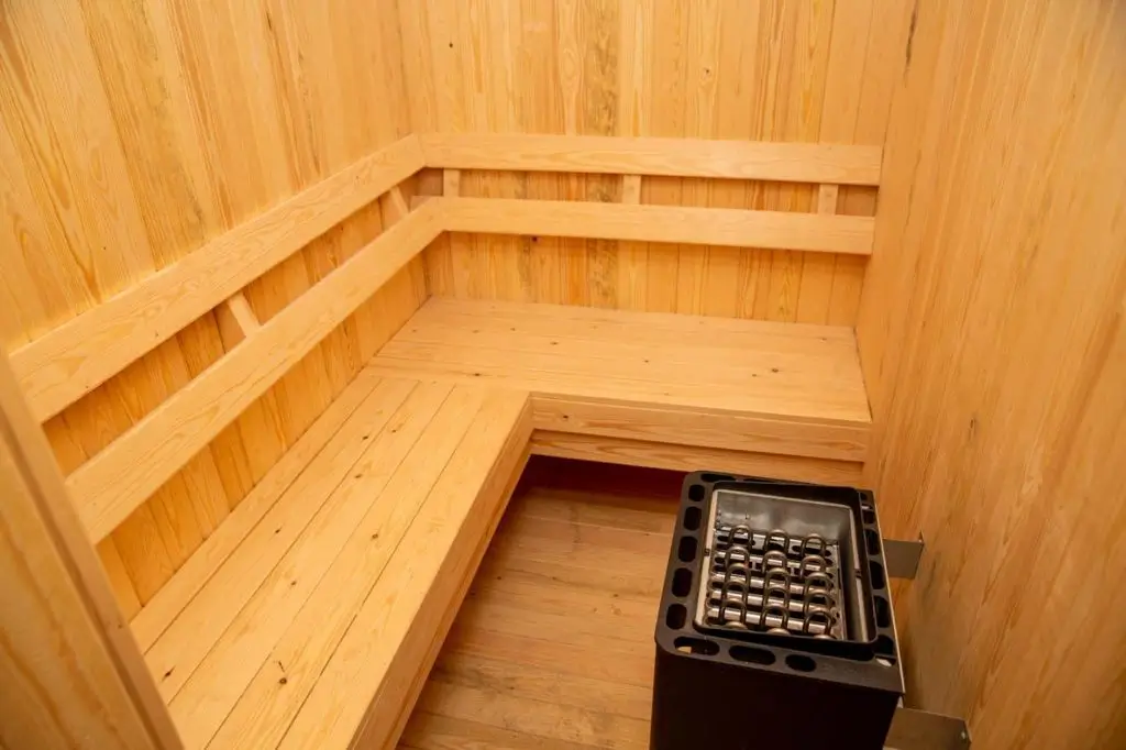 Wooden sauna room with benches and heater