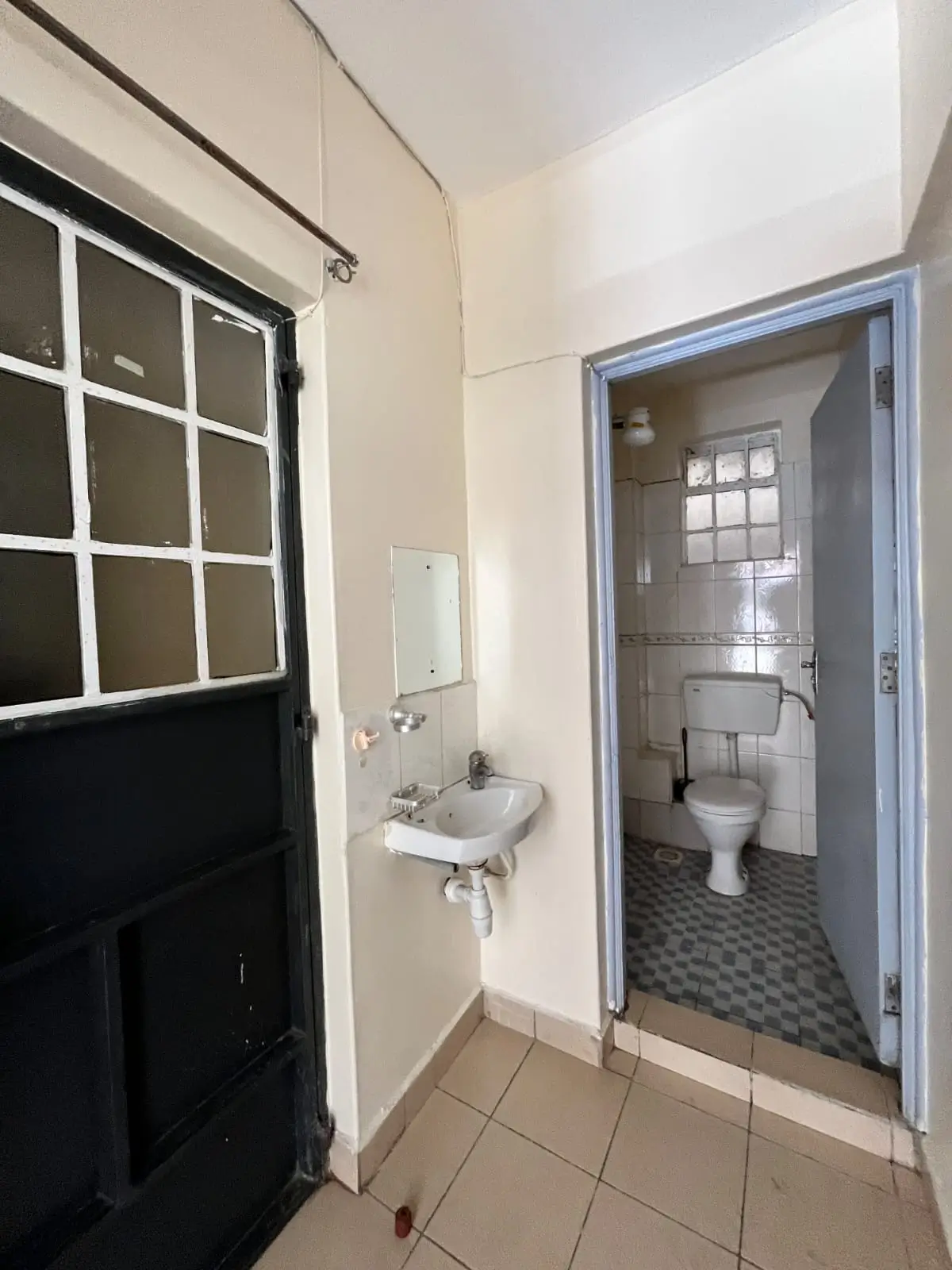Compact bathroom with toilet, sink, and tiled flooring