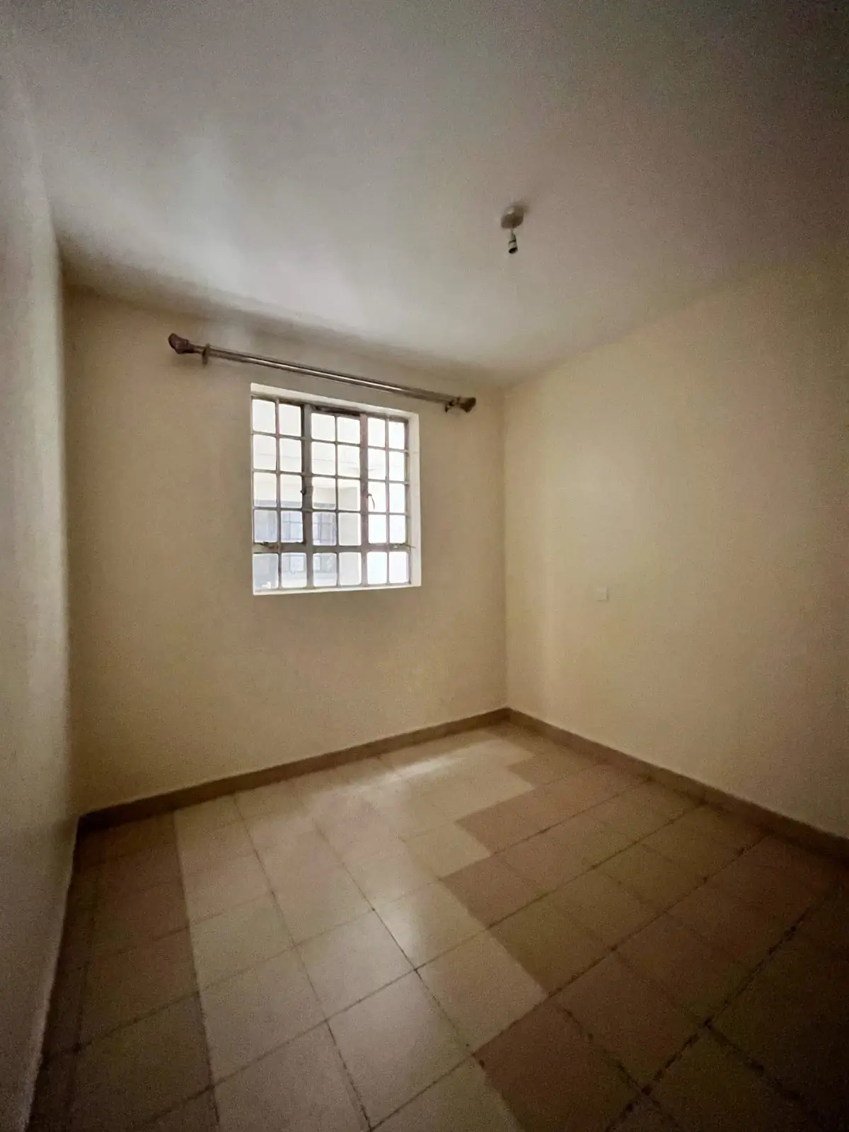 Empty bedroom with tiled floor and barred window