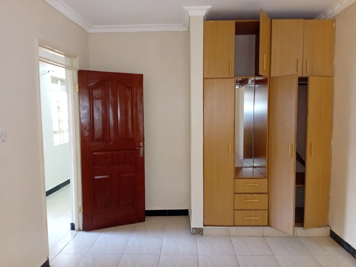 Bedroom with built-in wooden wardrobes and red entry door