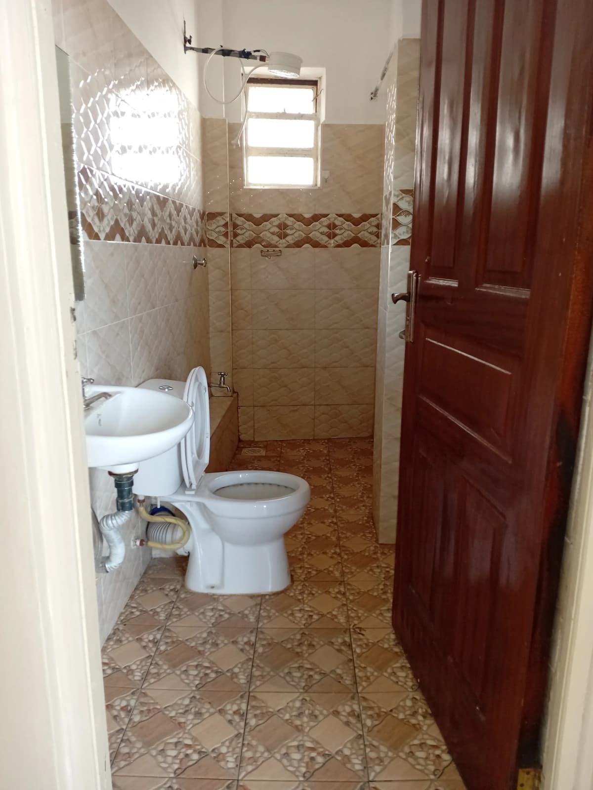 Compact bathroom with toilet, sink, and enclosed shower stall