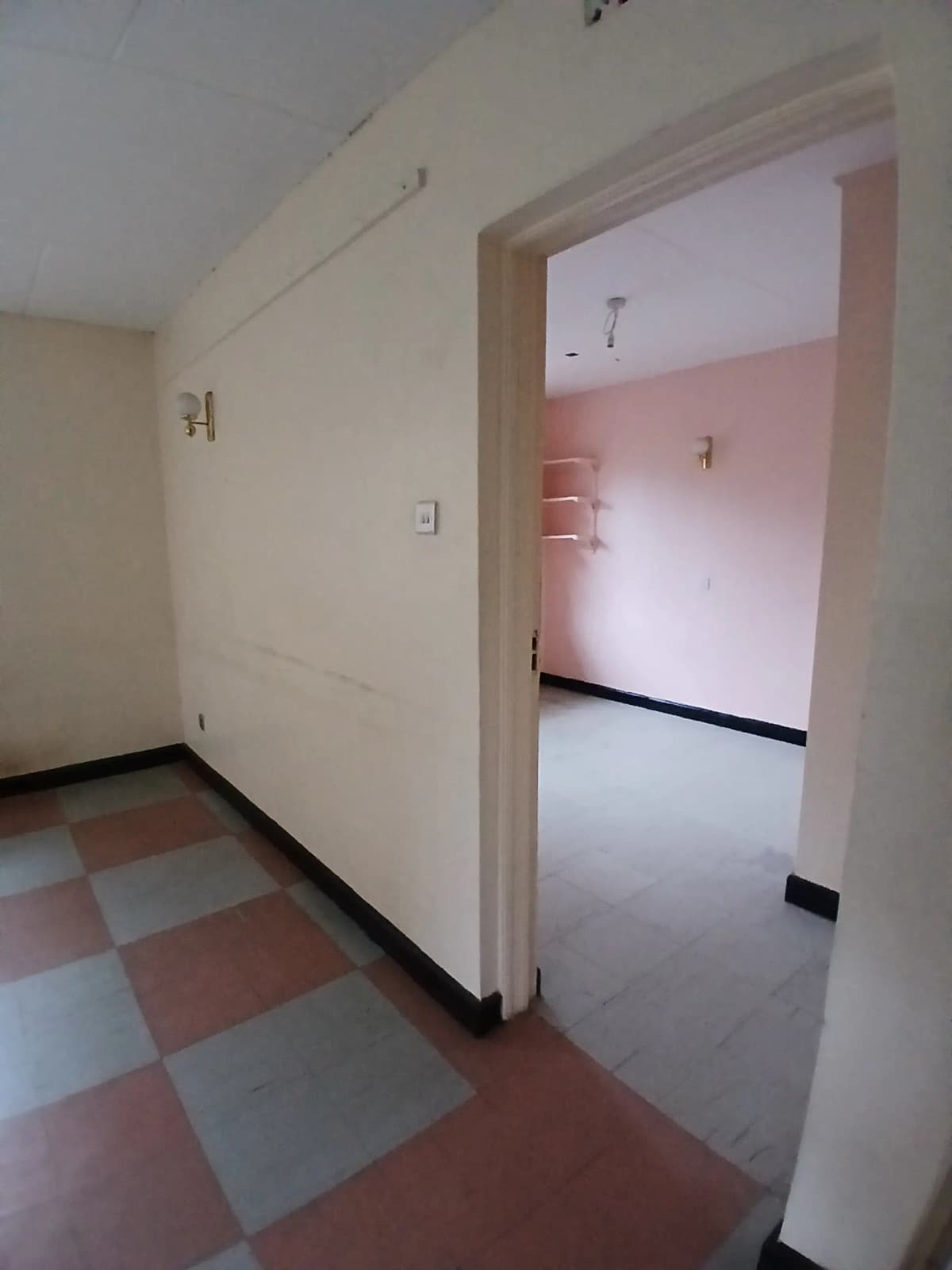 Corridor with checkered floor leading to pink bedroom